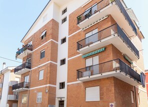 Un edificio residenziale a più piani con balconi, facciata in mattoni e cielo sereno.