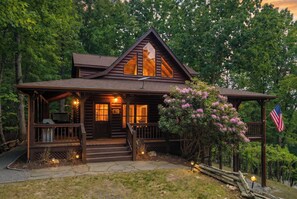 Une cabane en rondins avec un porche, des marches menant à l’entrée et un drapeau américain.