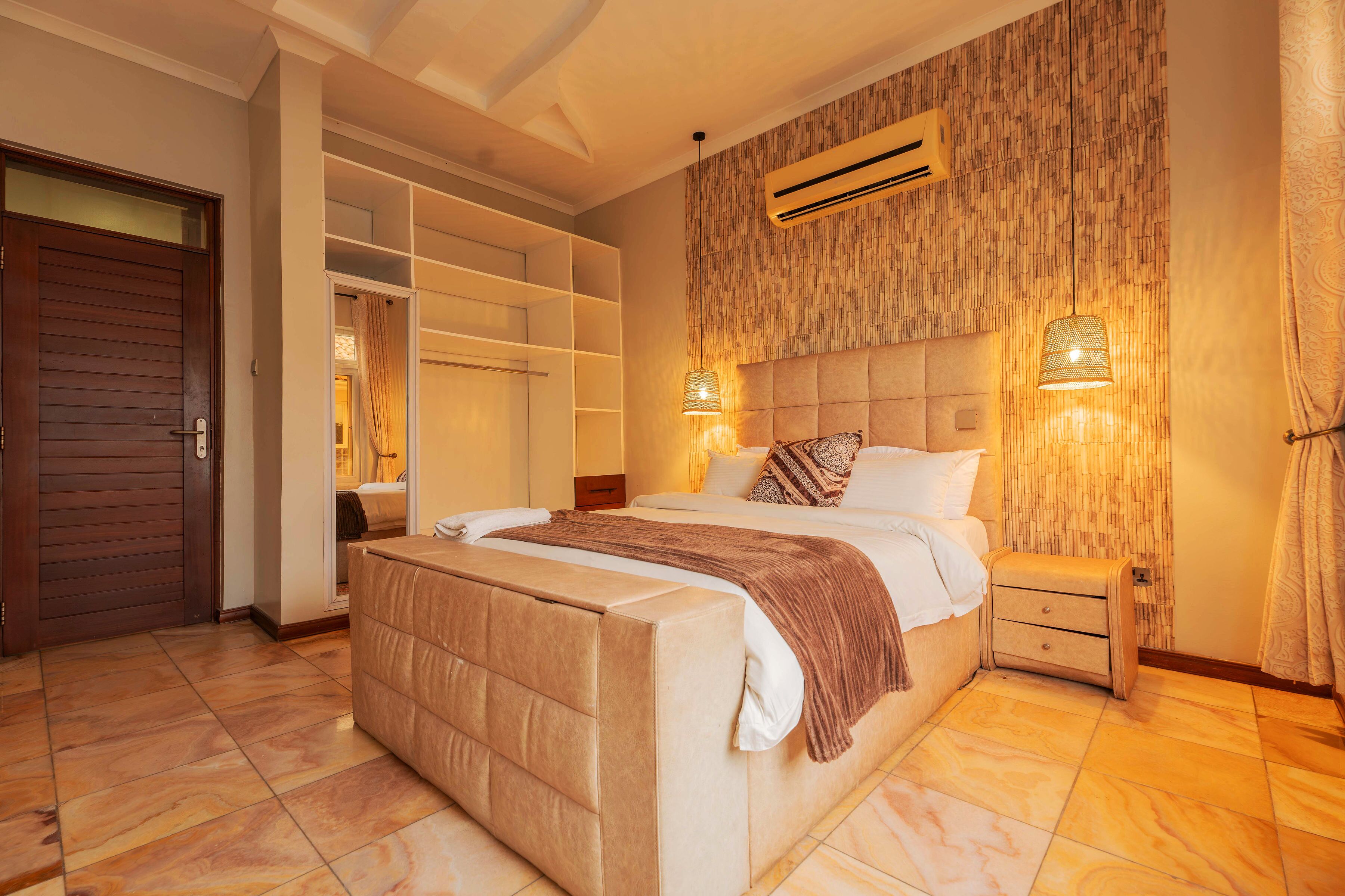 Un dormitorio con una cama grande, almacenamiento integrado, unidad de aire acondicionado y lámparas fijadas a la pared.