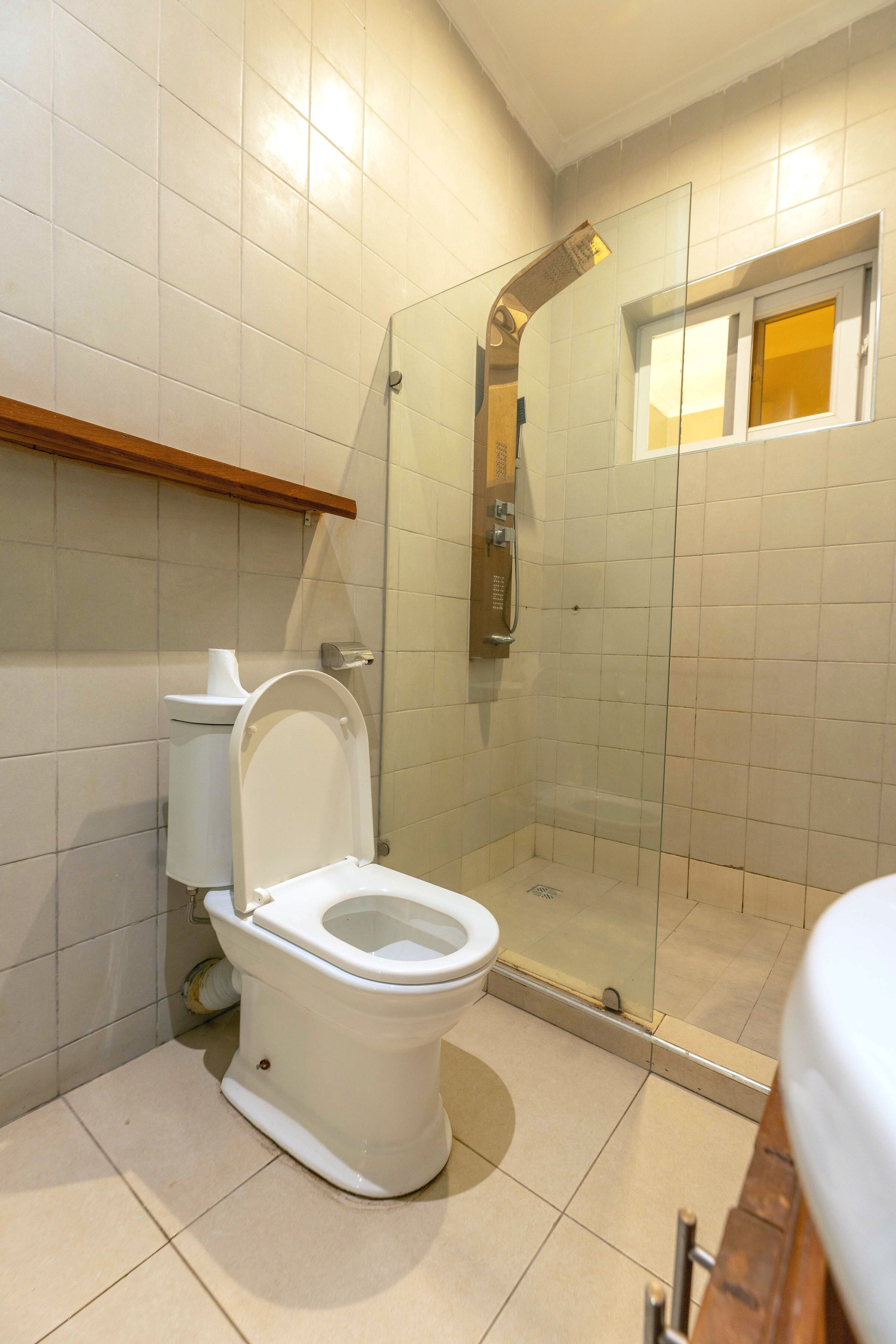 Un bagno con il water, cabina doccia e una finestra.
