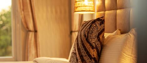 A bed with patterned pillows, a headboard, and a hanging lamp.