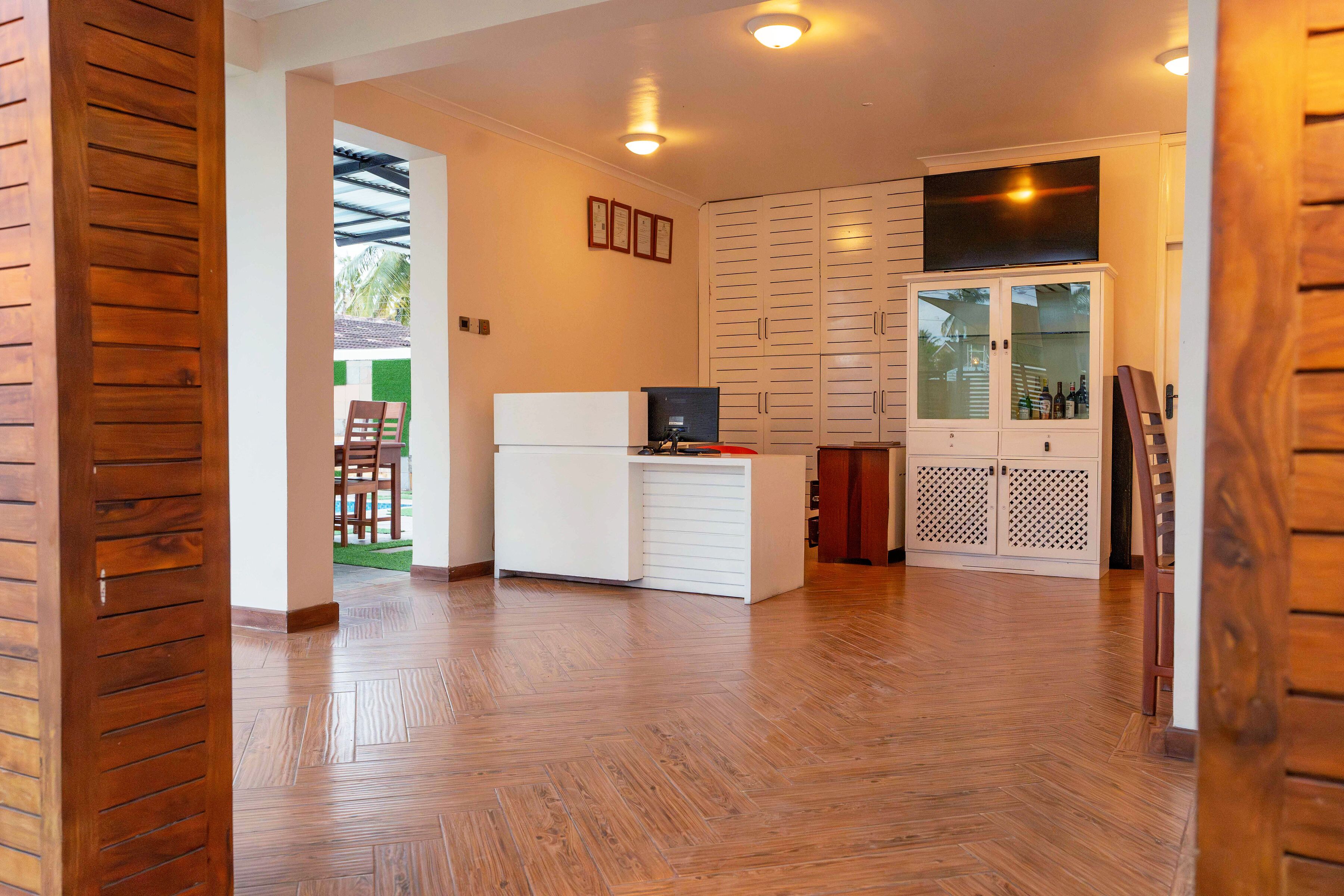 Una habitación con suelo de madera, un armario blanco, un televisor y un ropero.