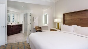A hotel room with a large bed, a wooden headboard, a vanity with a mirror, a small table with a lamp, and a chair. - 2-bedroom condo at the incredible Marriott Newport Coast Villas Resort (Newport Beach)