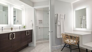 A modern bathroom with a large mirror, dark wooden cabinets, a glass shower enclosure, and a wicker chair. - 2-bedroom condo at the incredible Marriott Newport Coast Villas Resort (Newport Beach)