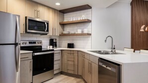 A modern kitchen with stainless steel appliances, wooden cabinets, and a white countertop. - 2-bedroom condo at the incredible Marriott Newport Coast Villas Resort (Newport Beach)