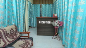 A reception area with a reception desk, a sofa, and curtains with a leaf pattern. - Silver Residency (Bhubaneshwar)