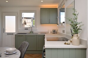 Una cocina con ventana, un lavamanos, una mesa de comedor y una planta en maceta.
