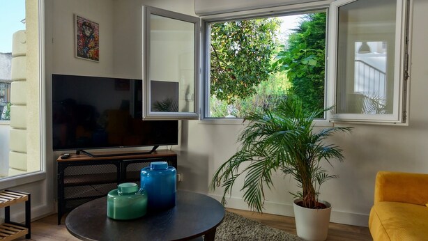 Ein Wohnzimmer mit Fernseher, Blumentopf und gelbem Sessel.