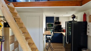Une cuisine compacte équipée d’une échelle en bois, d’un four à micro-ondes, d’une cuisinière et d’un réfrigérateur.