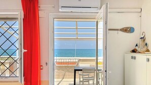 Una habitación con vistas al mar, un equipo de aire acondicionado, una cortina roja y una mesa con sillas.
