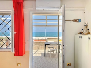 Ein Zimmer mit Meerblick, einer Klimaanlage, einem roten Vorhang und einem Tisch mit Stühlen.