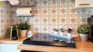 Una cocina con estufa integrada, un rollo de toallas de papel y plantas en macetas sobre la encimera.