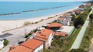 Un pueblo costero con una playa, una carretera y edificios, incluyendo uno con el letrero 'DIMORA COSTA VERDE'.