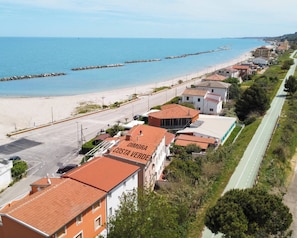 Eine Küstenstadt mit Strand, einer Straße und Gebäuden, darunter eines mit der Beschilderung 'DIMORA COSTA VERDE'.