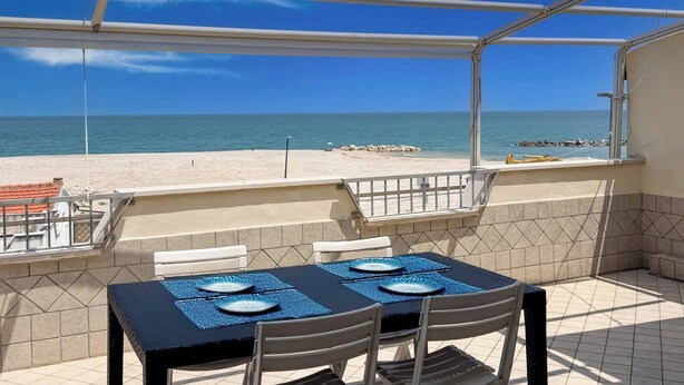 Un espacio de estar al aire libre cubierto con vista a la playa y al océano.