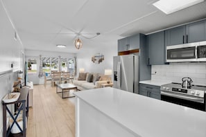 A modern kitchen with grey cabinets, a stainless steel refrigerator, and a built-in microwave. - Delphina in Anna Maria Island (Holmes Beach)