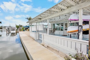 A waterfront property with a covered patio, outdoor seating, and a pool. - Delphina in Anna Maria Island (Holmes Beach)