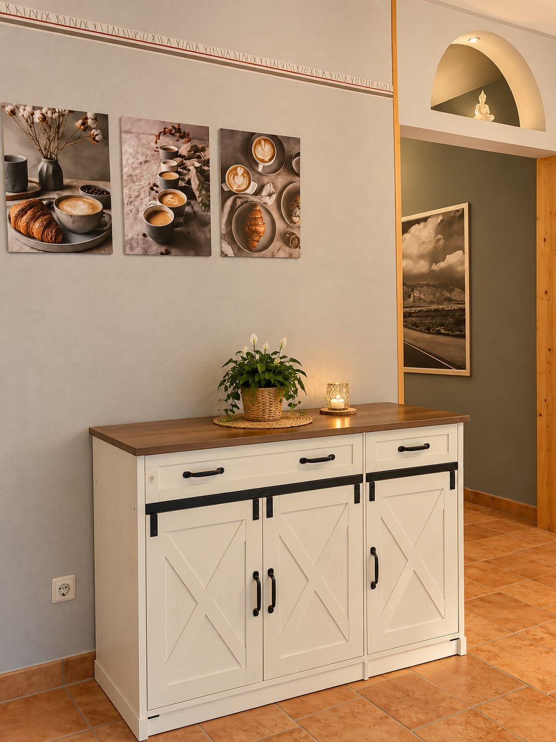 A white cabinet with black handles, a small plant, and a candle on top.