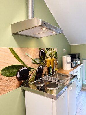 Cuina moderna amb campana d'extracció d'acer inoxidable, un rentaplat i una encimera amb branques d'olivera.