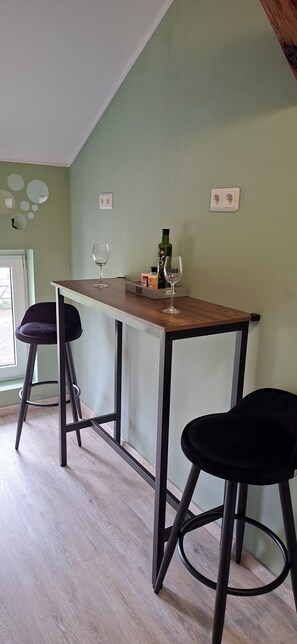 Una cocina con una mesa de madera, dos taburetes negros y una copa de vino.