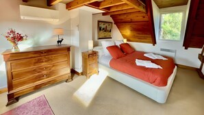 Un dormitorio con cama, cómoda, mesita de noche, lámpara y un cuadro en la pared.