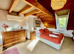 A bedroom with a bed, dresser, nightstand, lamp, and a painting on the wall. - Charming Guest Room near Tronçais Forest – Room (Meaulne-Vitray)