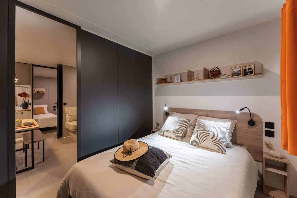 A modern bedroom with a bed, bedside tables, a desk, and a chair.