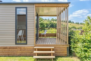 Una terraza de madera con un banco, una silla y una mesa.