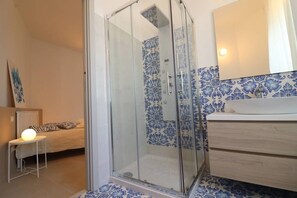 Une salle de bain avec une douche, un lavabo et un miroir.