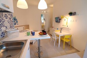 Une cuisine compacte avec un coin repas, comprenant un évier, une table avec des chaises et un panier à fruits.
