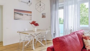 Un soggiorno moderno con zona pranzo, sedie trasparenti in vetro, tavolo in legno e divano rosso.