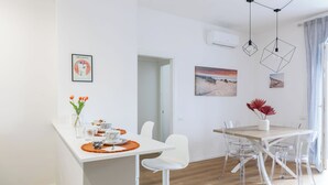 Un'area pranzo moderna con un tavolo bianco, sedie trasparenti e un lampadario a sospensione.