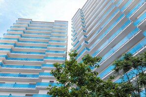 Un edificio moderno e di alta quota, caratterizzato da numerosi balconi e un cielo sereno sullo sfondo.
