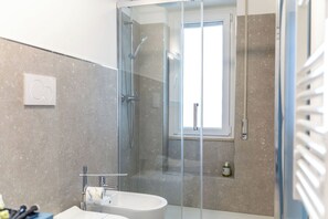 Een moderne badkamer met een douchecabine, een bad en een toilet.