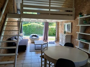 Una habitación con cama estilo altillo, una mesa de comedor, un sofá y vistas a un jardín.