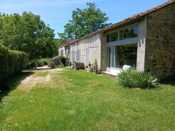 A stone building with a garden path leading to a modern extension with large windows.