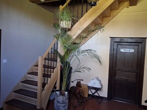 Un escalier en bois, agrémenté d’un pot de fleurs, d’une statue de cheval et d’une porte portant l’inscription « PRIVÉ ».