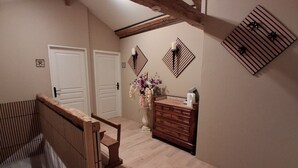 A room with a wooden staircase, a dresser, a vase with flowers, and a ceiling with exposed beams. - Bed and Breakfast 'La Chambre Des Cerfs' with Shared Pool, Private Terrace and Wi-Fi (Moissannes)