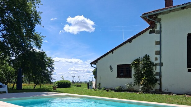 A swimming pool with a tiled edge, a white building with a window, and a clear blue sky. - Bed and Breakfast 'La Chambre Des Cerfs' with Shared Pool, Private Terrace and Wi-Fi (Moissannes)