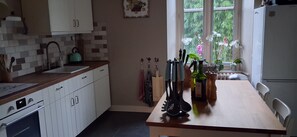 Una cocina con armarios blancos, un lavamanos, una estufa y una ventana con plantas.