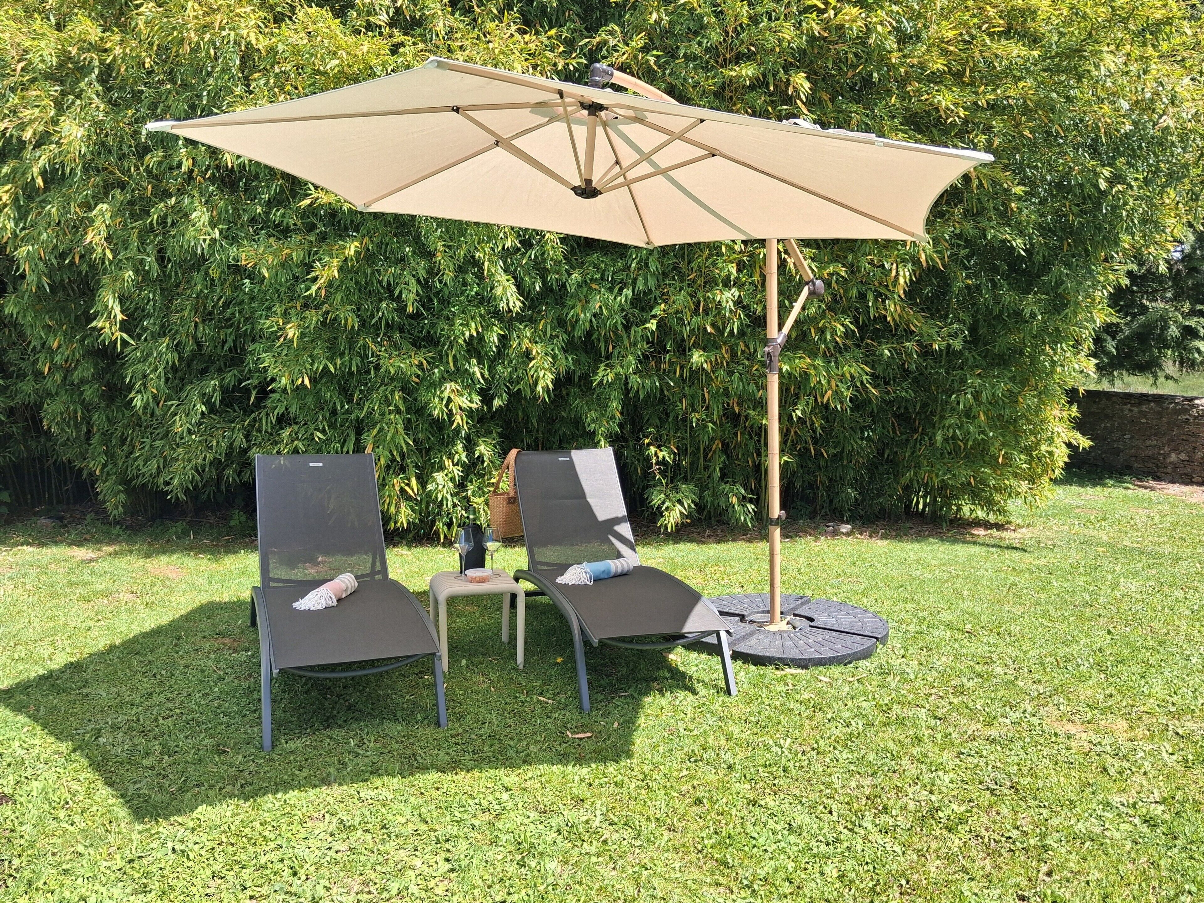 Une terrasse avec deux chaises et une table, un parasol et un poteau en bambou.