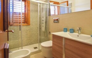 Ein Badezimmer mit Duschkabine aus Glas, Toilette und Waschbecken mit zwei blauen Behältern.