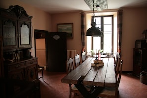 A dining area with a wooden table, chairs, a cabinet, and a radiator.