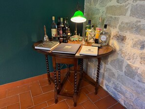 A wooden table with books, bottles, and a lamp against a stone wall. - Villa di Pietro – Historic/newly renovated stone villa with a pool and ocean view! (Sicilia)