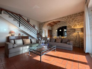 Ein Wohnzimmer mit einer Couch, einem Glastisch, einer Treppe und einer Steinwand.