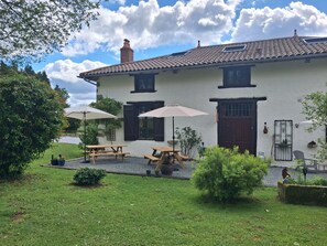 A house with a tiled roof, a chimney, and a garden with picnic tables and umbrellas. - Bed and Breakfast 'La Chambre Du Rouge-gorge' with Shared Pool, Private Terrace and Wi-Fi (Moissannes)