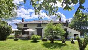 Une maison à deux étages, avec un toit en tuiles, un porche à l’avant et une pelouse bien entretenue.