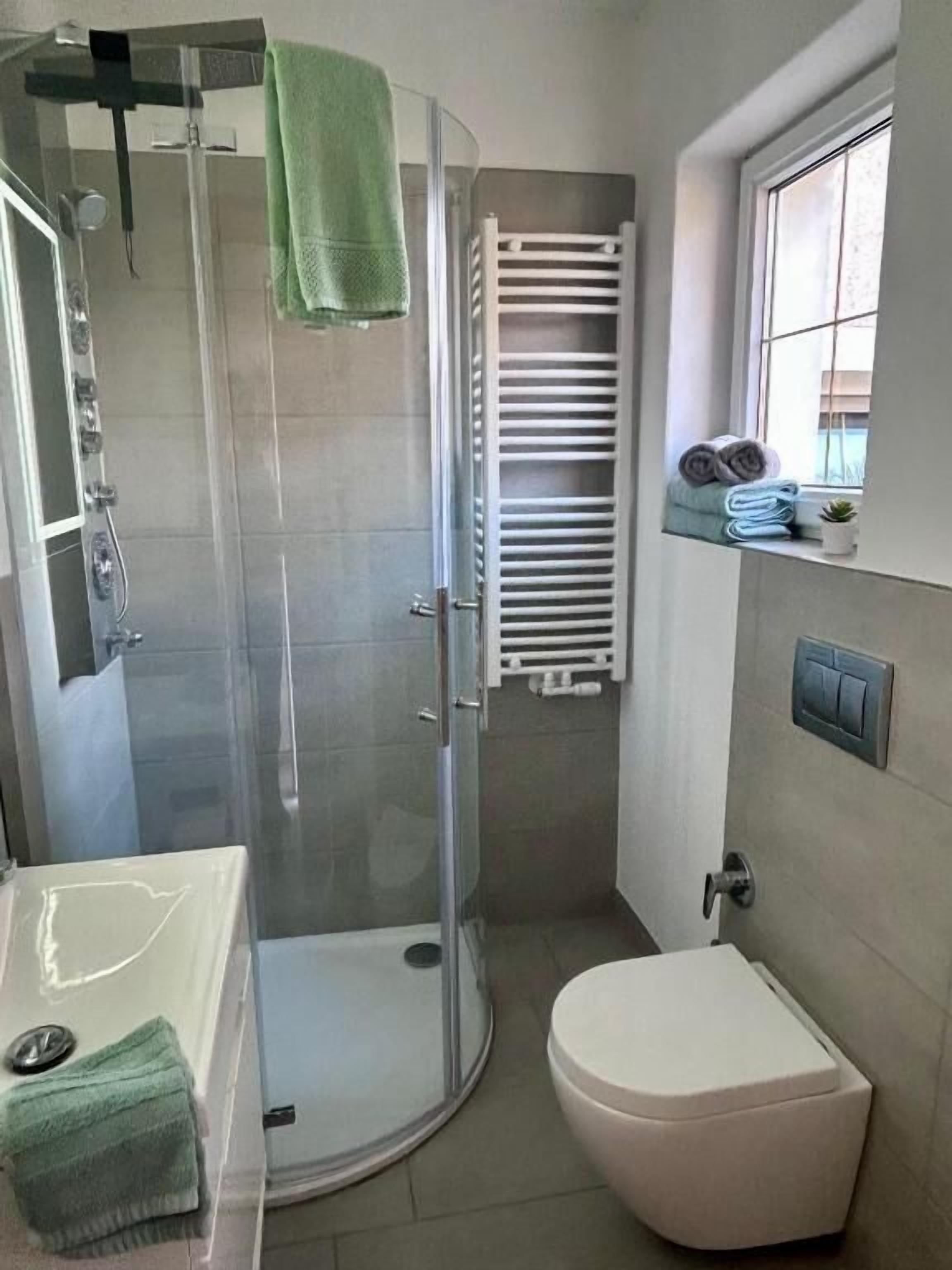 Ein Badezimmer mit Duschkabine, Toilette und Fenster.