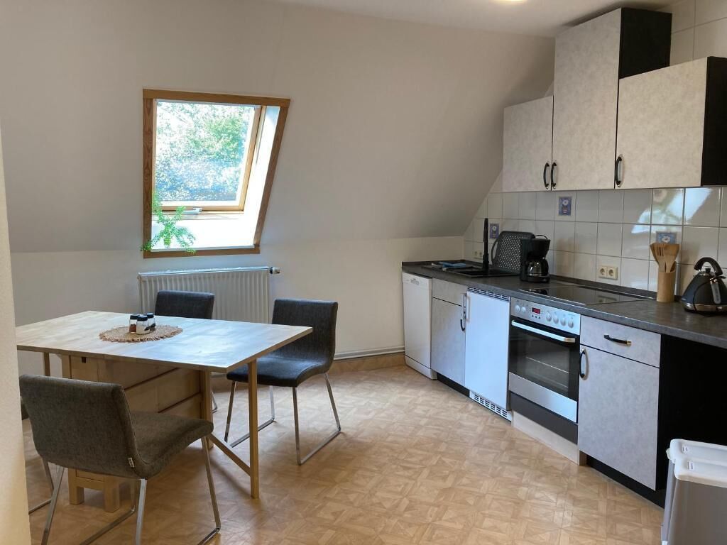 Una cocina compacta con una mesa de comedor, sillas, una ventana y electrodomésticos integrados.