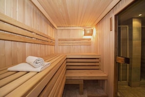 Una sauna con bancos de madera y un banco con toalla.